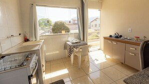 A small kitchen with a window, a table with chairs, and a sink. - Apto c/ Varanda,  Garagem e Vista das Montanhas (Angra dos Reis)