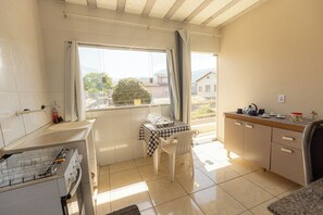 Eine kleine Küche mit Fenster, einem Tisch mit Stühlen und einem Spülbecken.