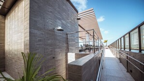 Een modern gebouw met een gebogen gevel, een terras en een heldere lucht.