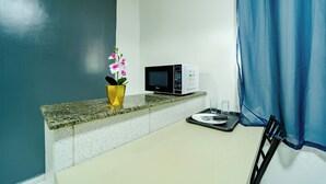 A small kitchenette with a microwave, a tray with a plate and utensils, and a potted orchid. - Flat com Wi-Fi a Poucos Metros do Aeroporto (Fortaleza)