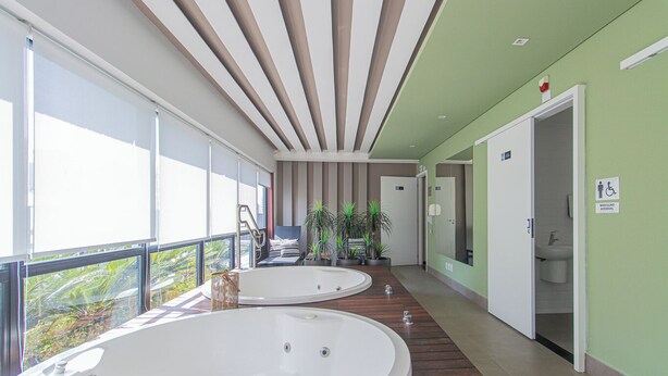 A modern bathroom with two large tubs, a wooden floor, and a balcony with a view. - Loft a 10min do metrô c Academia - Vila Mariana (São Paulo)