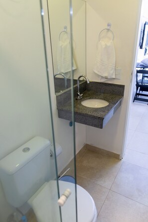 Ein Badezimmer mit einem Marmorwaschbecken, einer Toilette und einer Duschkabine aus Glas.