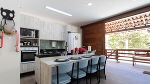Una cocina moderna con una isla central, electrodomésticos integrados y un comedor con sillas y una mesa.
