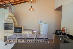 A kitchen with a brick oven, a refrigerator, and a sink. - Casa c Piscina e Churrasqueira na Praia Maranduba (Ubatuba)