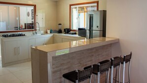 Una cocina moderna con una isla central, taburetes de bar, un refrigerador y una cafetera.