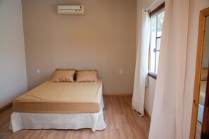 Een slaapkamer met een bed, een raam en een airconditioning.