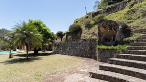 Una escalera de piedra que sube una colina, rodeada de césped, con una palmera y un edificio al fondo.