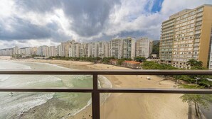 Vista sulla costa con palazzi alti, spiaggia sabbiosa e onde oceaniche.