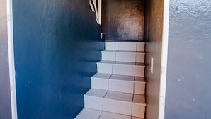 A staircase with white steps and a wooden handrail, leading to a dark interior space.