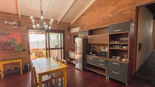 Eine moderne Küche mit Essbereich, ausgestattet mit einem Holztisch und -stühlen, einem Einbauofen und einer Mikrowelle.