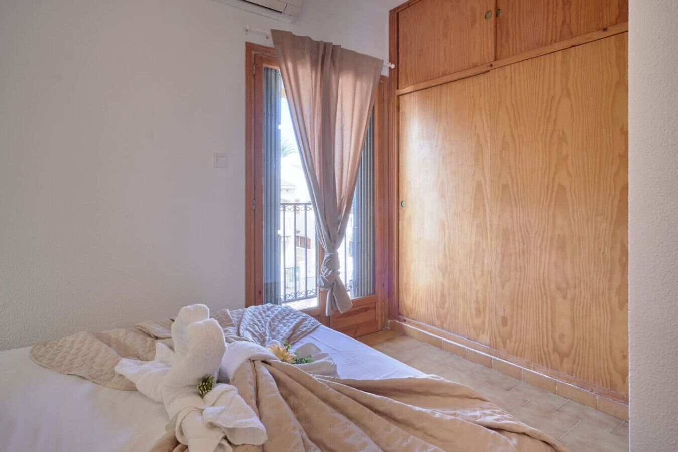 Una camera da letto con un letto, un armadio in legno e una finestra con tende.