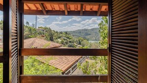 Blick durch ein hölzernes Fenster mit Ziegeldach auf ein Wohngebiet mit Häusern und Grünflächen.