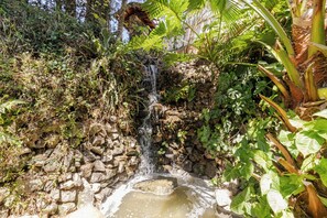 Eine natürliche Felsformation mit einem kleinen Wasserfall und einem Becken am Fuße.
