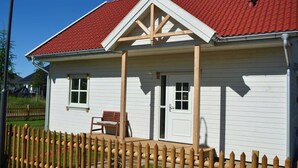 A white building with a red roof, a wooden porch, and a wooden fence. - Vacation cottage Hus Hygge Warin (Warin)