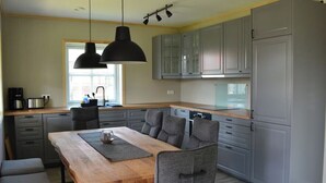 A modern kitchen with grey cabinets, a wooden dining table, and two pendant lights. - Vacation cottage Hus Hygge Warin (Warin)