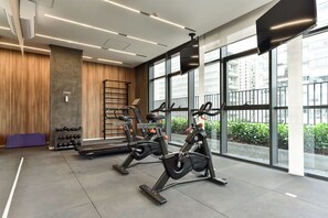 Ein modernes Fitnessstudio mit Ergometer, Laufband und Wandfernseher.