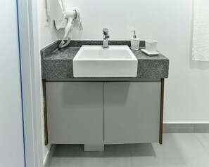 Un baño moderno con un lavamanos blanco, encimera de granito y una toalla colgada en la pared.