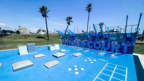 A blue outdoor gym with exercise equipment, palm trees, and a clear sky. - The Tides of Galveston (Galveston)