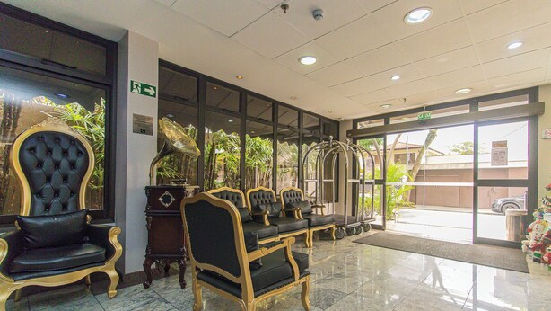 Un hall d’entrée doté d’un sol en marbre, de fauteuils noirs et dorés et d’une grande fenêtre donnant sur l’extérieur.