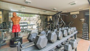 Une salle de sport équipée de divers appareils d’exercice, notamment des haltères et un tapis de course.