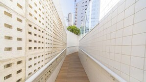 A narrow corridor with tiled walls and wooden flooring, leading to a higher level. - Apto com Ar e 2 Dorm na Vila Mirim perto da Praia (Santos)