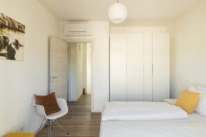 Ein Schlafzimmer mit einem Bett, einem Sessel, einer Klimaanlage und einer Tür zu einem anderen Raum.