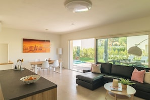 A modern living room with a dining area, a black leather sofa, a round coffee table, and a painting on the wall. - Villa Fortuna by Garda FeWo in Manerba (Manerba del Garda)