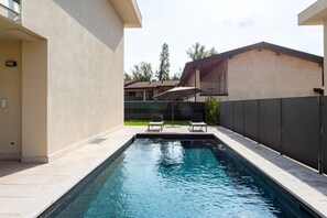Une piscine avec deux chaises longues et un espace abrité.