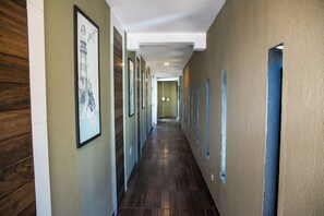A hallway with framed artwork on the walls, wooden paneling on one side, and a blue accent wall on the other. - Loft com Smart Lock e Ar perto do Projeto Tamar (Ubatuba)