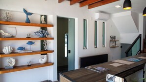 Zona de recepción con estantes de madera que exhiben objetos decorativos, un mostrador de recepción con documentos y una escalera.