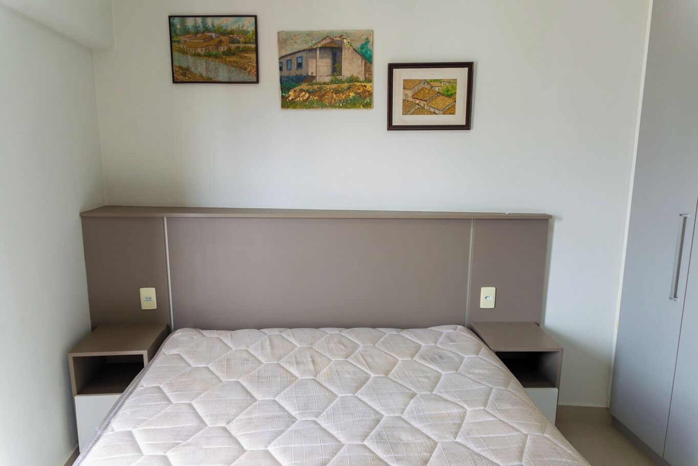 Un dormitorio con cama, cabecera y una obra de arte colgada en la pared.