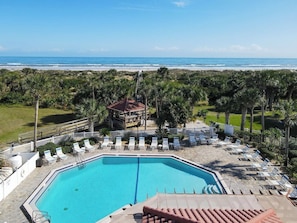 A swimming pool with lounge chairs, a small gazebo, and a view of the beach. - Sunny Beach Community Condo (St. Augustine)