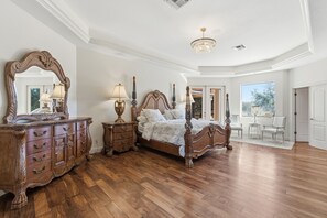 Um quarto espaçoso com uma cama grande, uma cômoda de madeira e um lustre.