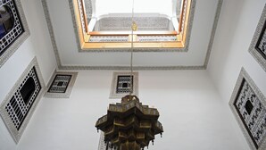 Une pièce aux hauts plafonds, ornée de motifs géométriques complexes sur les murs et dotée d’un lustre central.