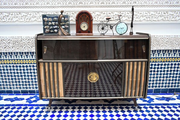 A vintage radio cabinet with a clock, a bicycle, and decorative items. - Riad Saphira Fès (Fes)