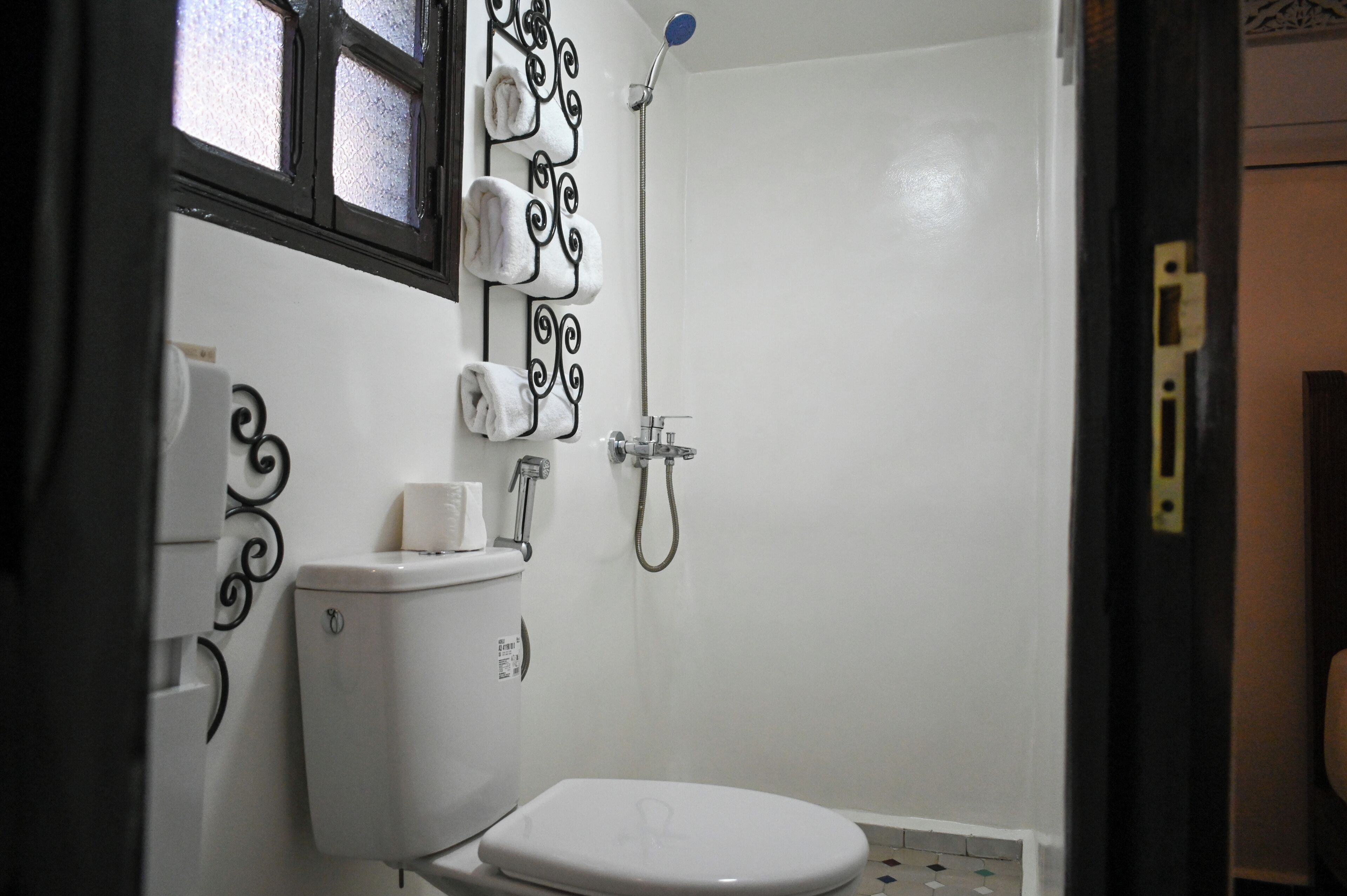 Un baño pequeño y funcional con inodoro, ducha y toallero.