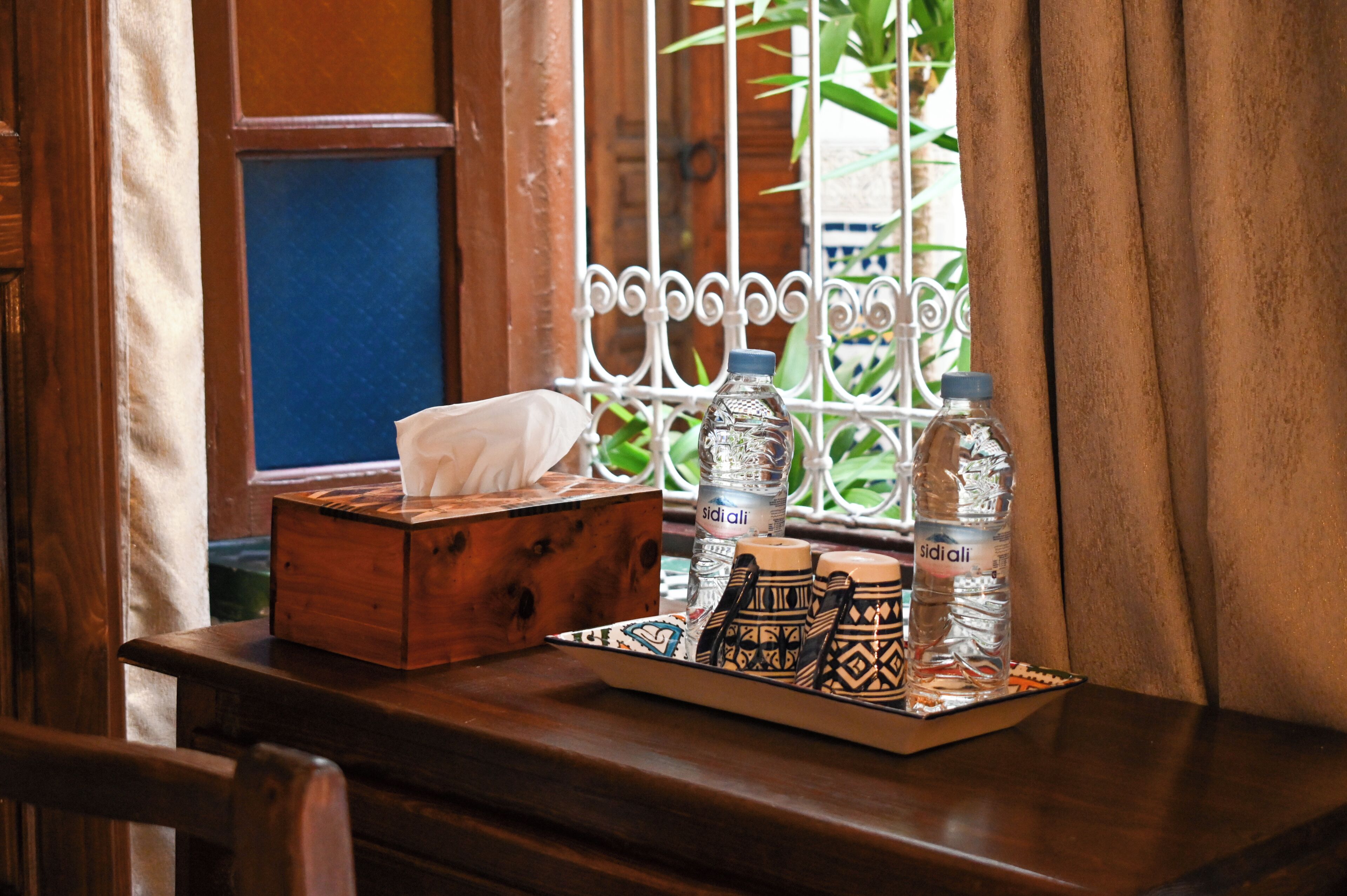 A wooden table with a tray containing water bottles, a tissue box, and decorative items.