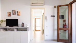 Une chambre d’hôtel équipée d’un téléviseur à écran plat, d’une petite table, d’un climatiseur fixé au mur et d’une porte avec un panneau en verre.