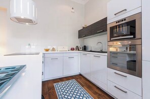 A modern kitchen with white cabinets, stainless steel appliances, and a patterned rug. - Spacious and elegant apartment, rue d'Antibes, in the heart of Cannes. (Cannes)