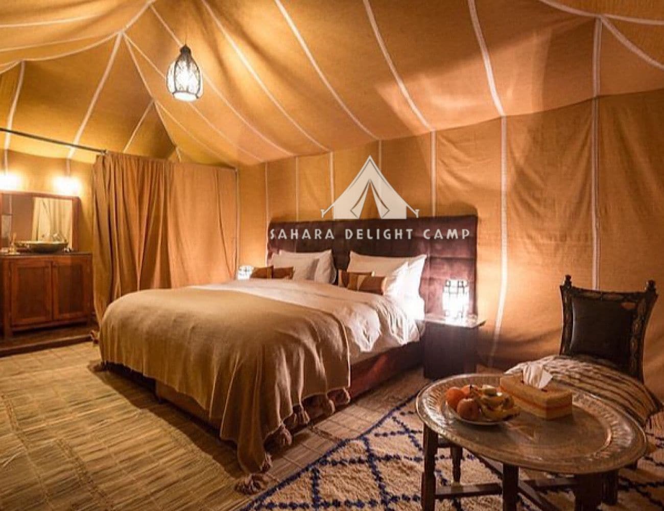 Una habitación con tienda de campaña, cama, mesita de noche, silla y mesa con comida.
