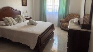 Ein ordentlich eingerichtetes Schlafzimmer mit Bett, Stuhl, Kommode und Spiegel.