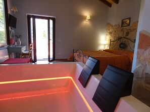 A room with a bed, a massage table, a desk, and a stone wall. - Scappo in Umbria, Casale Rusinè (Narni)