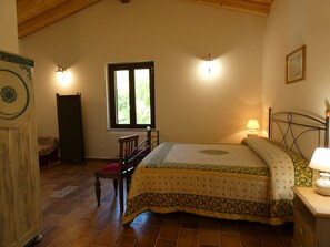 Ein Schlafzimmer mit Bett, Stuhl, Kleiderschrank, Fenster und einer Wandlampe.