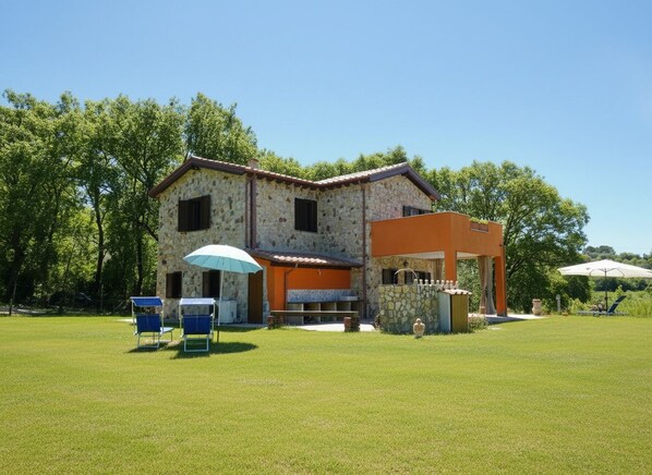 Ein Steinhaus mit Terrasse, Sitzgelegenheiten im Freien und einem kleinen Garten.