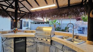 An outdoor kitchen with a built-in grill, a sink, and a stone countertop. - Luxury Oasis Between Downtown LA & Orange County (Downey)