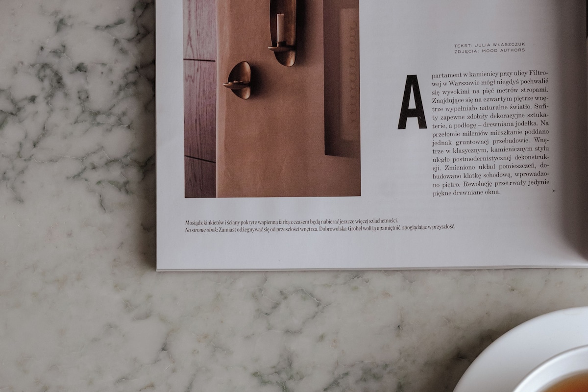 A magazine page with a marble surface, a cup of tea, and a book.