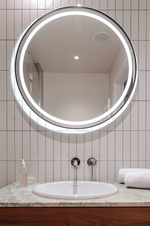 A bathroom with a round mirror, a sink, and a towel. - BELMONTE Hotel Ustronie Morskie (Ustronie Morskie)