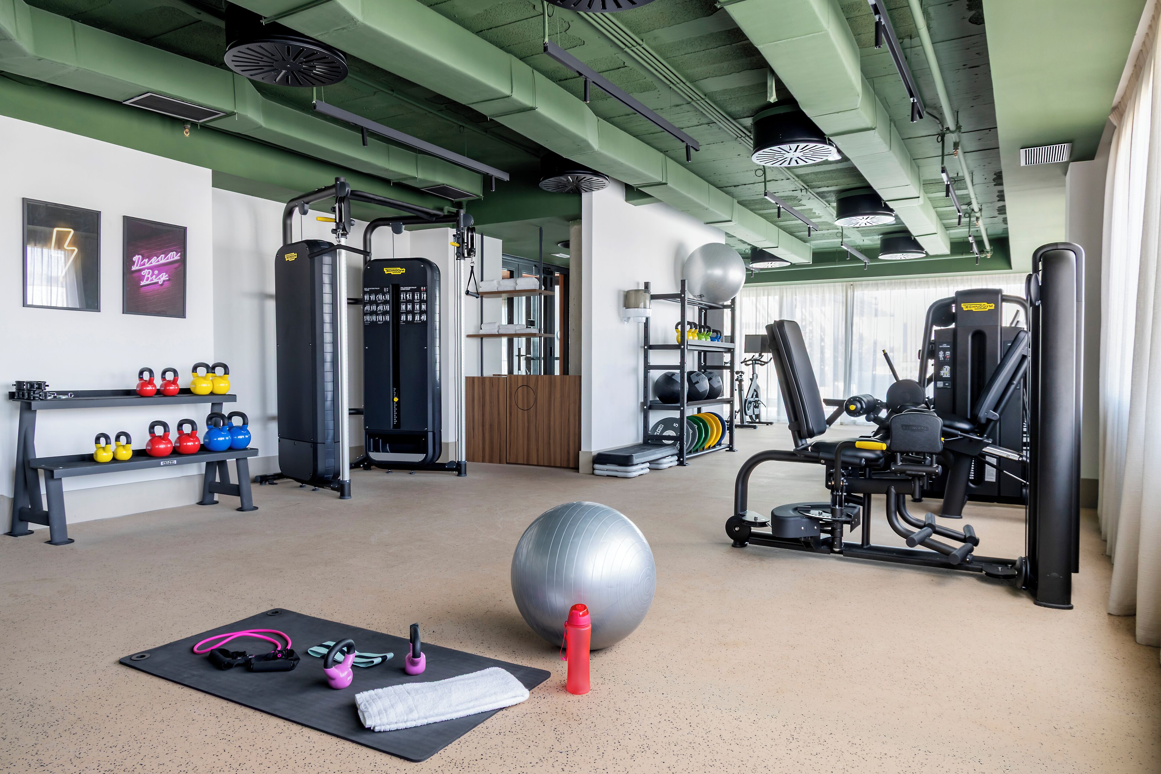 A gym with exercise equipment, kettlebells, and a large exercise ball.