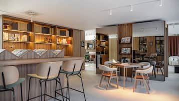 Un interior moderno con paneles de madera, taburetes de bar y una zona de comedor con sillas y una mesa.