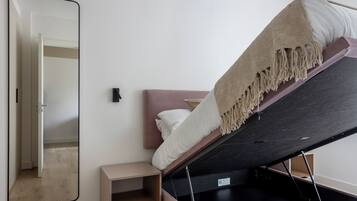 A bedroom with a bed, a bedside table, a mirror, and a wardrobe.
